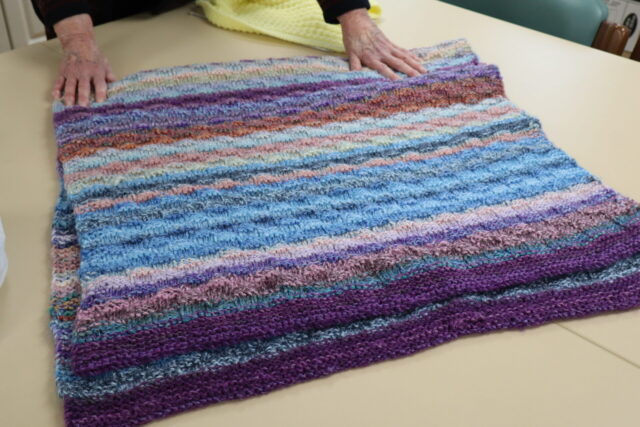 a completed project of a knitted blanket folded on a table 