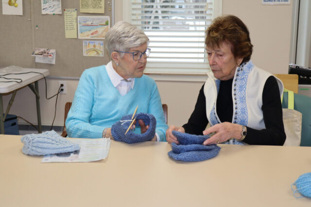 Two women collaborating on a knitting project during a Good Yarn Knitters group session.